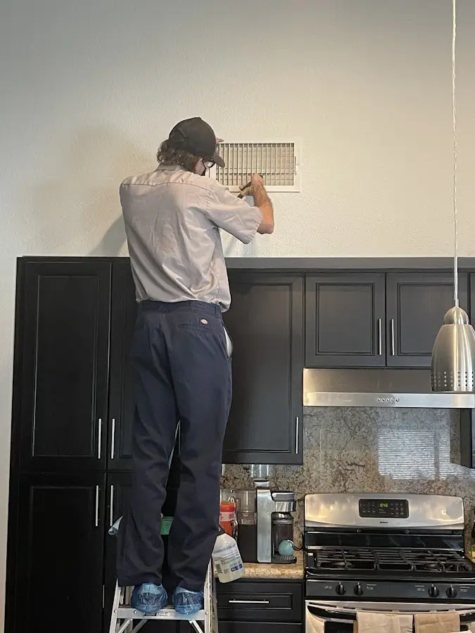 Technician inspecting an air vent during HVAC service in Hopkins